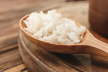 Fototapeta na wymiar Spoon with boiled rice on wooden table, closeup