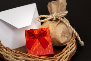 dos regalos y sobre de san valent&iacute;n en coraz&oacute;n de mimbre fondo negro 