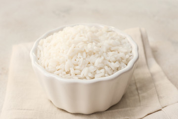 Bowl with boiled rice on light background