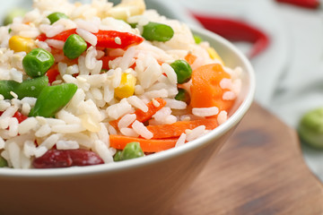 Bowl with boiled rice and vegetables on table, closeup