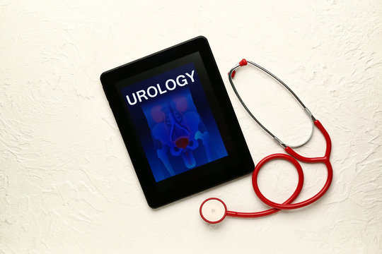 Tablet computer with with picture of urogenital system on screen and stethoscope on white background