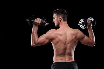 Fototapeta na wymiar Rear view of young muscular shirtless sportsman exercising with dumbbells