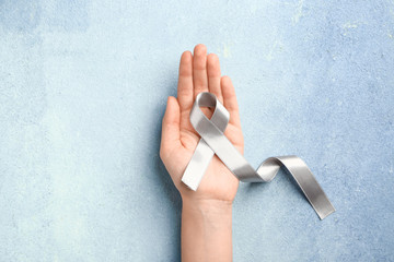 Female hand with Parkinson's awareness ribbon on color background
