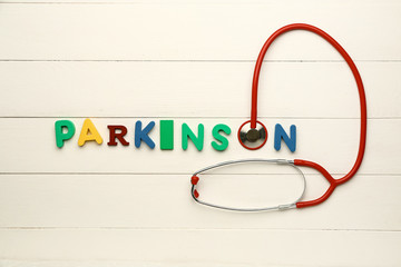 Text PARKINSON with stethoscope on white wooden background