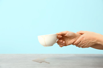 Woman suffering from Parkinson syndrome with cup of coffee against color background