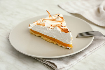 Plate with piece of tasty lemon pie on table