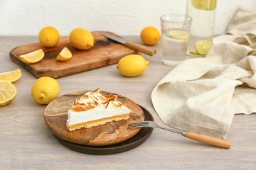 Plate with piece of tasty lemon pie on table