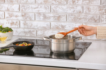 Woman preparing tasty rice in kitchen