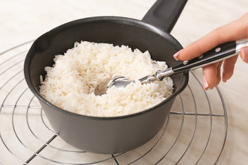 Woman preparing tasty rice in saucepan