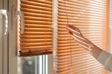 Woman opening blinds on window