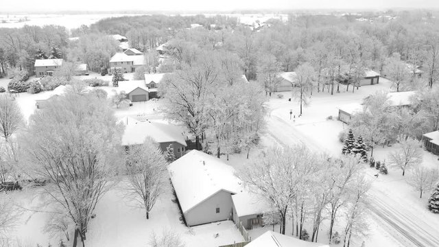 Very scenic small town neighborhood, trees covered with snow, homes blanketed in white, aerial drone view.