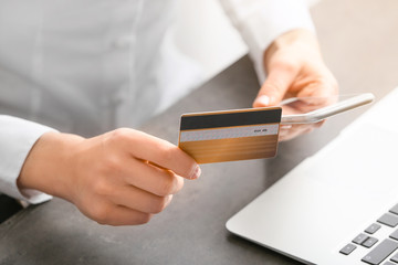 Woman with laptop, mobile phone and credit card at table, closeup