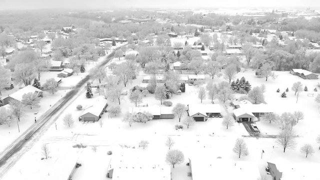 Very scenic small town neighborhood, trees covered with snow, homes blanketed in white, aerial drone view.