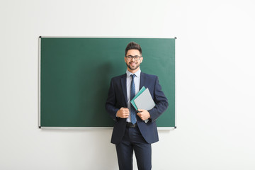 Male teacher near blackboard in classroom