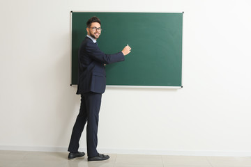 Male teacher writing on blackboard in classroom