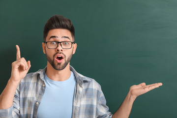 Male teacher with raised index finger near blackboard in classroom