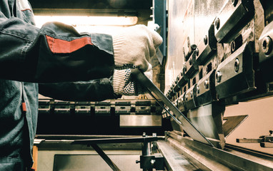Worker bends metal on the machine. The old machine. A worker works in a factory.