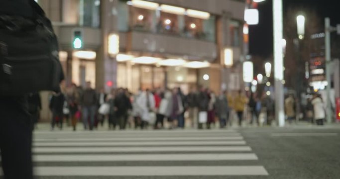 東京都中央区、銀座四丁目交差点の夜景。信号を渡る人々。背景はボケている。