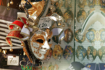 A gold Venetian mask hangs for sale in a small Italian shop.