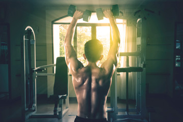 Young man lifting dumbbell at gym