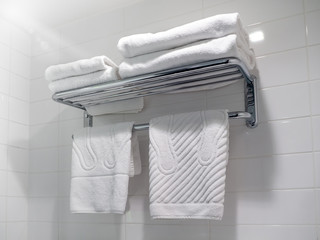 Clean white towels on a shelf in the bathroom in a hotel room. Close-up bath accessories