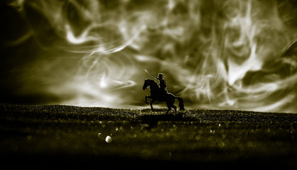 World war officer (or warrior) rider on horse with a sword ready to fight and soldiers on a dark...