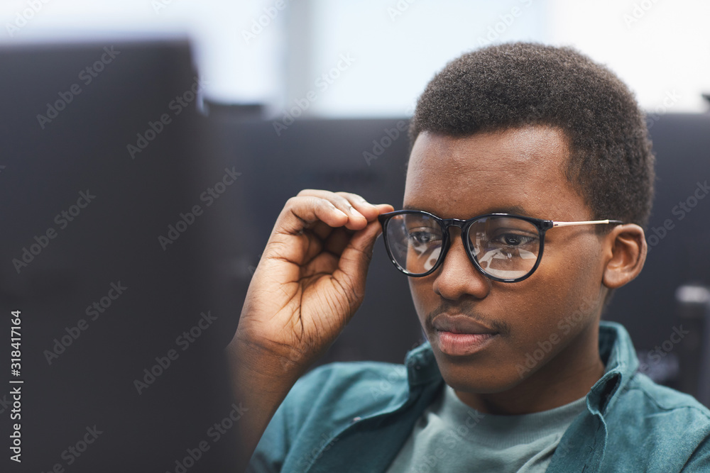 Wall mural high angle portrait of african-american man adjusting glasses while using computer in class of colle