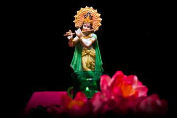 Hindu god Krishna. Statue with lotus flowers on a black background