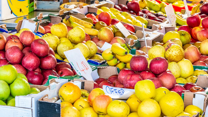 Red, yellow, green apples and bananas on display for sale at European Italian local farmers market. Colorful fresh ripe organic fruits, vegetarian food, from farm garden agricultural harvest produce.