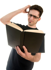 A young man who looks confused by a book