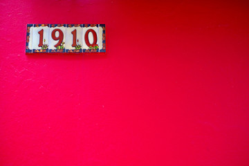 Number 1910, one thousand nine hundred and ten, nineteen hundred and ten, digits on tiles on a red...