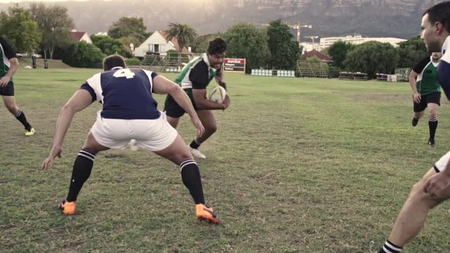 Rugby player displaying his skills of tackling with the opponent during the match. Strong young men playing a game of rugby on the field.