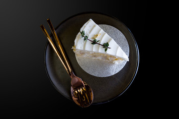 Piece of coconut sponge cake with white whipped cream on brown plate.