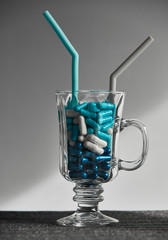 Medicine Blue and white capsules in the cocktail glass on the gray background