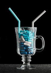 Medicine Blue and white capsules in the cocktail glass on the  black background