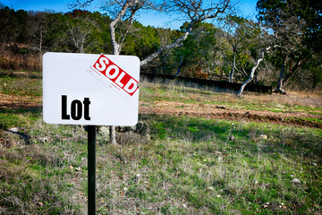 Land sale. Sign "LOT sold" with empty space for advertisement.