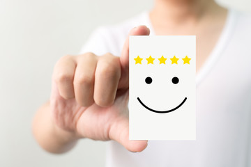 Customer service experience and business satisfaction survey. Man holding card with smiley face with five star - obrazy, fototapety, plakaty