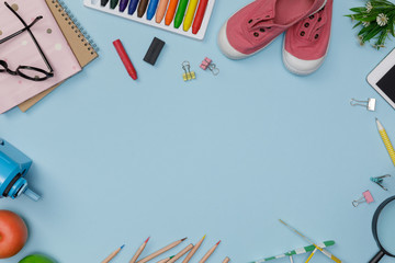 Creative flatlay of education blue table with student books, shoes, colorful crayon, eye glasses, empty space isolated on blue background, Concept of education and back to school