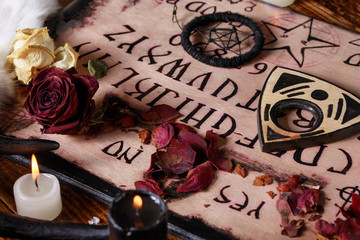 Spiritual board ouija with candles close-up. Mystical ritual of calling dead spirits. Macro.