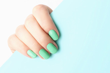Female hand with trendy manicure Neo-mint on blue background with copy space - obrazy, fototapety, plakaty