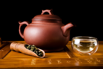 Chinese tea ceremony. Clay teapot with green oolong tea Tieguanyin on a black background with a...