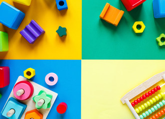 Wooden kids toys on colourful paper. Educational toys blocks. Toys for kindergarten, preschool or daycare. Copy space for text. Top view, mock up
