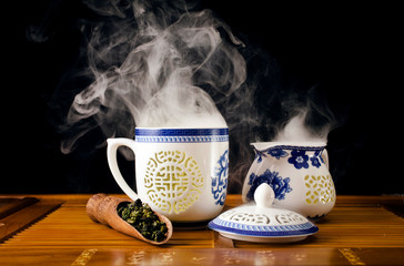 Chinese tea ceremony. Ceramic tea cup with green oolong tea Tieguanyin with vapour on a black...