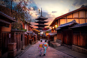 Two geishas wearing traditional japanese kimono among at Yasaka Pagoda and Sannen Zaka Street in Kyoto, Japan.