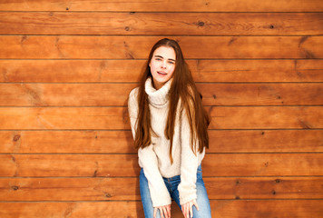 Young beautiful teenager girl posing on a wooden wall background