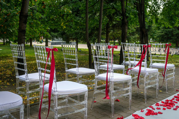 Fototapeta na wymiar Chairs stand in rows decorated for the wedding ceremony outdoor. Registration of marriage in summer park.