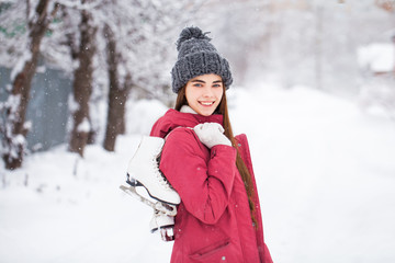 Fototapeta na wymiar Happy beautiful brunette woman with ice skates go to the rink, winter outdoors
