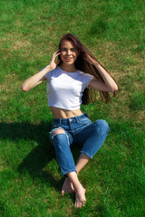 Fototapeta premium Portrait of a young beautiful girl resting on the lawn in the park