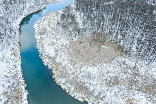 picturesque winter landscape. small river and bare trees under snow. drone photography