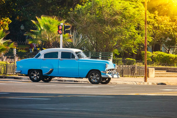 Old blue classic American car stands at an intersection in front of a traffic light